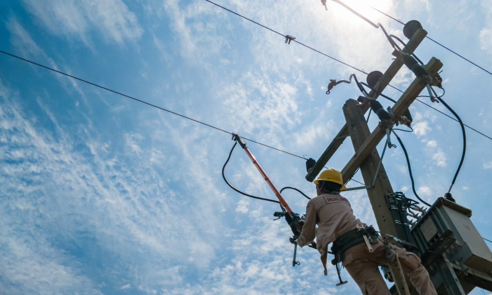 The power lineman closing a transformer on energized high-voltage electric power lines.